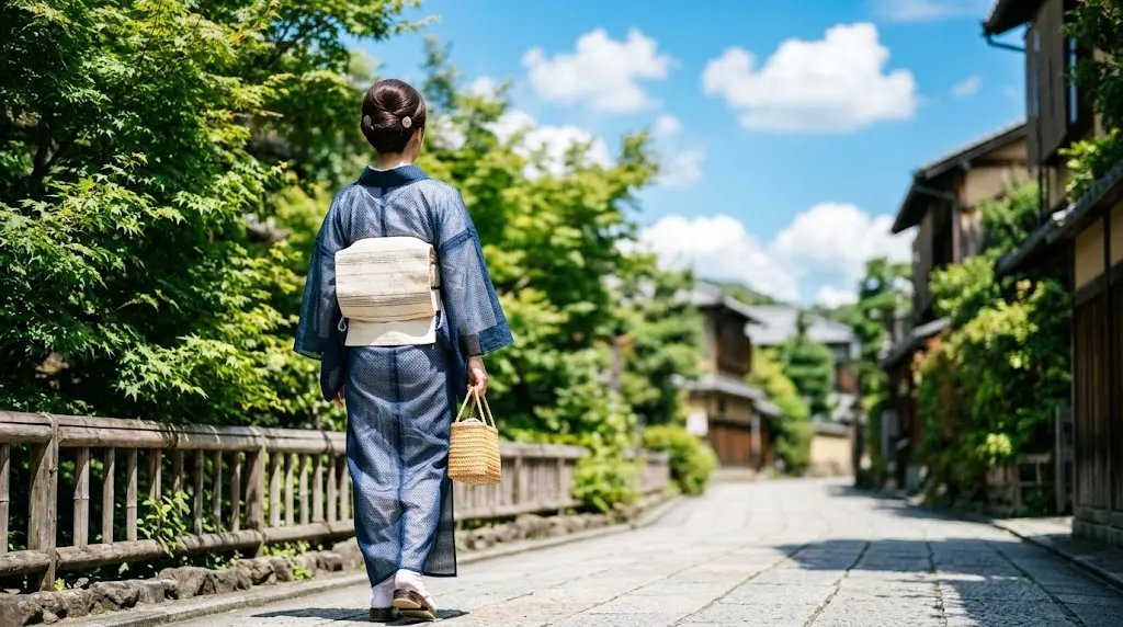 夏の青空のもと透け感のある夏紬に麻の帯を締めた涼やかな後ろ姿